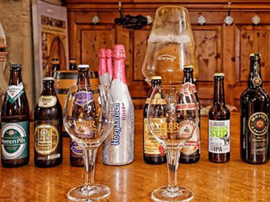Beer bottles and glasses are on a wooden table.