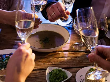 Glasses rise to toast over the food on the table.