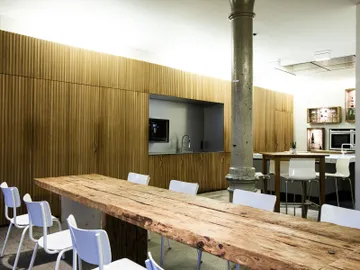 There is a wooden table in a modern, minimalistic kitchen.