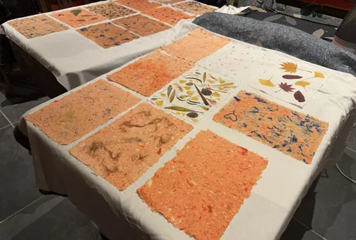 Handgemachte Papierblätter mit Blumenmustern auf Tischen.