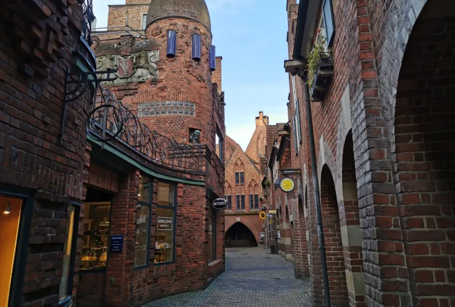 Narrow cobblestone street with historic red-brick buildings.