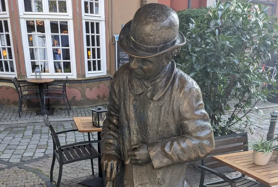 Bronzestatue eines Mannes mit einem Stock im Freien.