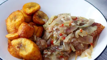 Fried plantains and fish with onions on plate.