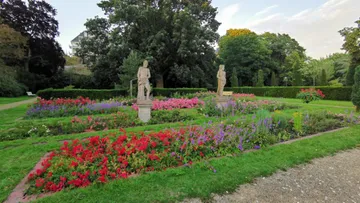 Statuen und leuchtende Blumen im formellen Garten.