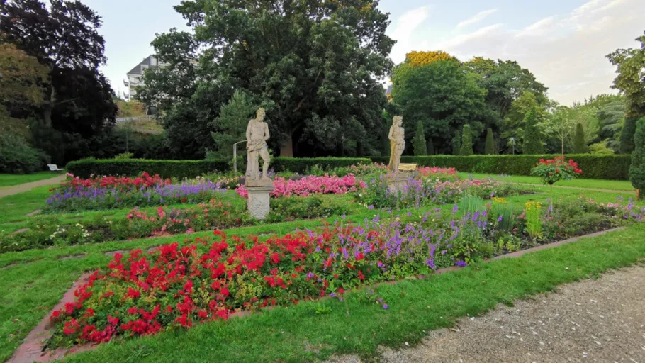 Statues and vibrant flowers in formal garden.