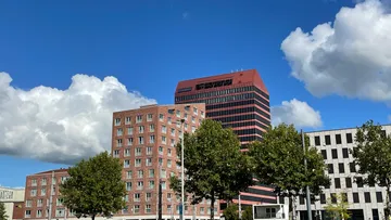 Tall red building with trees and blue sky.
