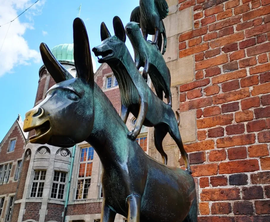 Bronzestatue gestapelter Tiere gegen eine Backsteinmauer.