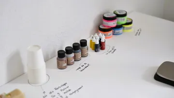 Assorted paint bottles and jars on table.