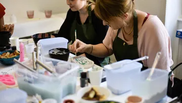Two women painting pottery at a workshop.