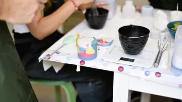 Person making candles at a table workshop.