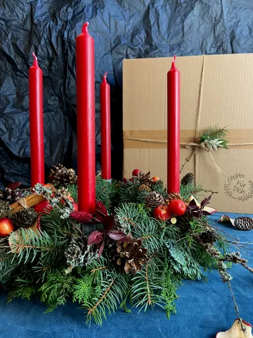 Festive centerpiece with red candles and greenery.