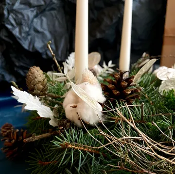 Kerzen, arrangiert mit Tannenzapfen und grünem Herzstück.