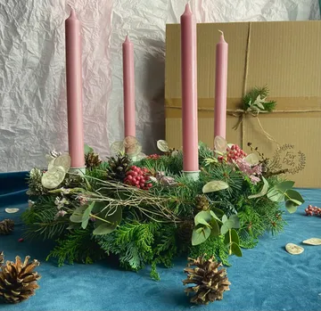 Pink candles on a festive floral wreath.