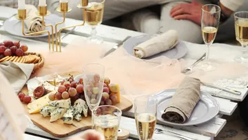 Cheese platter with grapes and champagne on table.