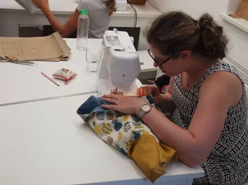 Woman sews a colorful bag on a sewing machine.