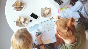 Three people discussing at a table with coffee cups.