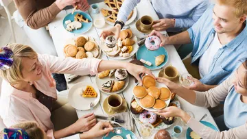 People sharing pastries and drinks at a table.