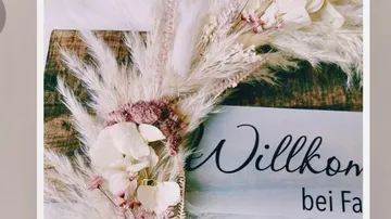Trockenblumen mit Willkommen-Schild.