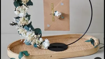 Dekoratives Blumenarrangement mit Geschenkkarte auf dem Ständer