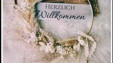 Decorative wreath with 'Herzlich Willkommen' sign.