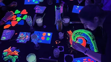 People painting with neon colors under UV light.