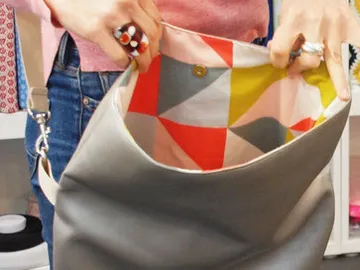 A person is holding a gray bag with colorful inner lining.