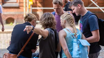 Group of people looking at device outdoors.