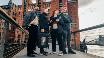 Four people on a walkway near buildings.