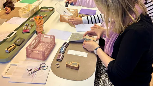 People crafting with stamps and paper at a table.