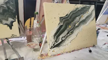 Canvas with abstract painting, wine glass nearby.