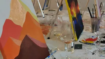 Easels and wine glasses on painting table.