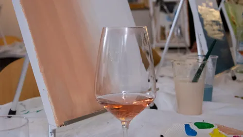 Wine glass on table with painting supplies.