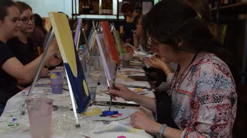 Women painting on canvases in a studio.