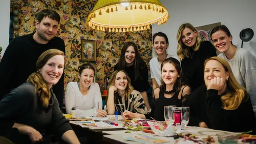 Group of people smiling around a table in a cozy room.