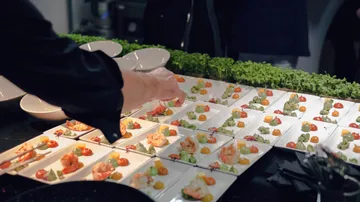 Koch serviert Gourmet-Vorspeisen auf quadratischen Gerichten.