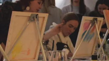 People painting on canvases in a group setting.