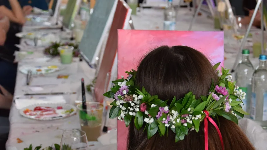 Person painting with floral crown in art class.