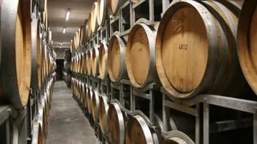 Wooden barrels on metal racks in cellar.