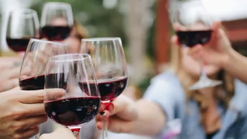 Hands holding wine glasses in a toast.