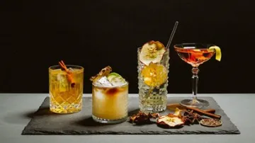 Four cocktails with garnish on slate.