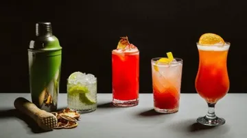 Assorted cocktails with shaker on table.