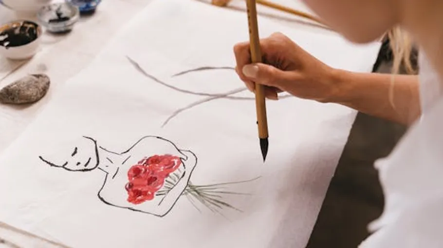 Person, die eine Blumenfigur mit einem Pinsel malt.