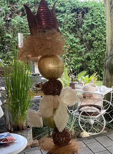 Dekorative Gnomenfigur mit Kugeln und Krone, draußen.