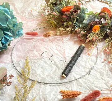 Floral wreath assembly with wire on paper.