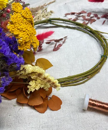Colorful dried flowers arranged around green wreath base.
