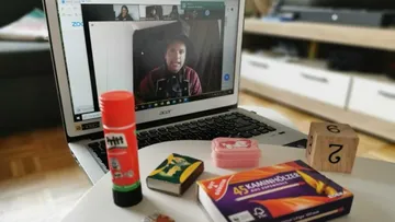 Video call on laptop with assorted items on table.
