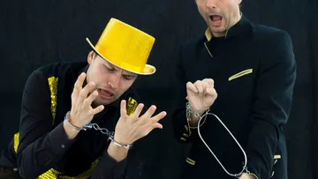 Two magicians with handcuffs on stage.