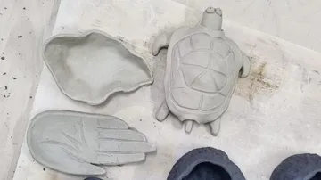 Clay turtle and hand molds on table.