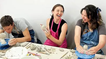 Three people laughing during pottery class