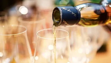 Wine being poured into glasses, blurred background.